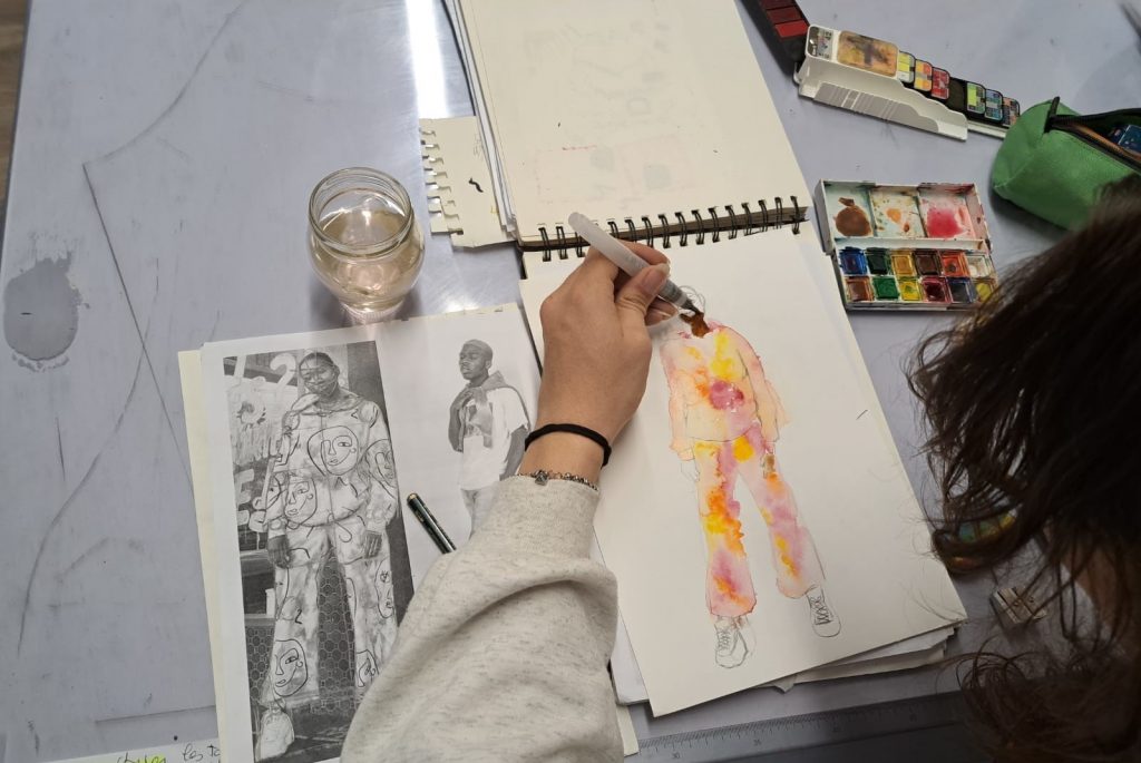 Élève en train de dessiner des modèles de mode lors d'un cours de dessin à l'école de mode.
