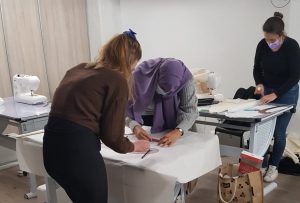 Élève en train de coudre un vêtement lors d'un cours de couture à l'école de mode.