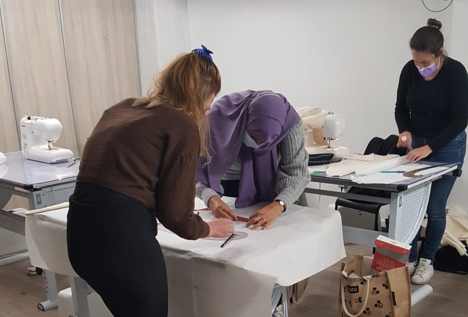Élève en train de coudre un vêtement lors d'un cours de couture à l'école de mode.