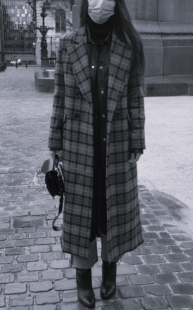 Femme élégante en manteau à carreaux, sac à main noir et bottes en cuir