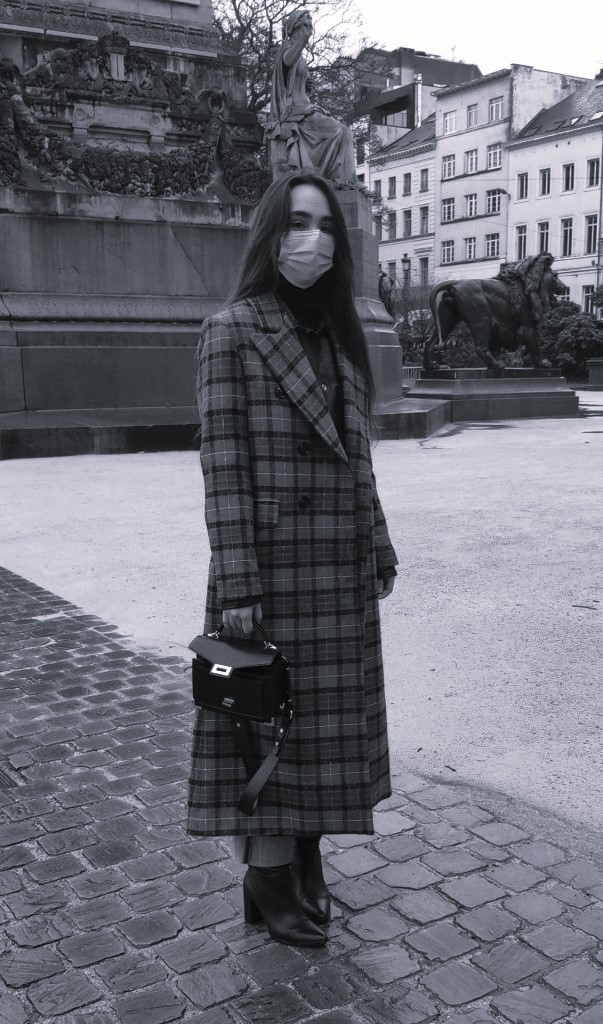 Femme élégante de profil en manteau à carreaux, sac à main noir et bottes en cuir