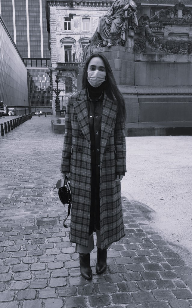 Femme à Bruxelles en manteau à carreaux, sac à main noir et bottes en cuir